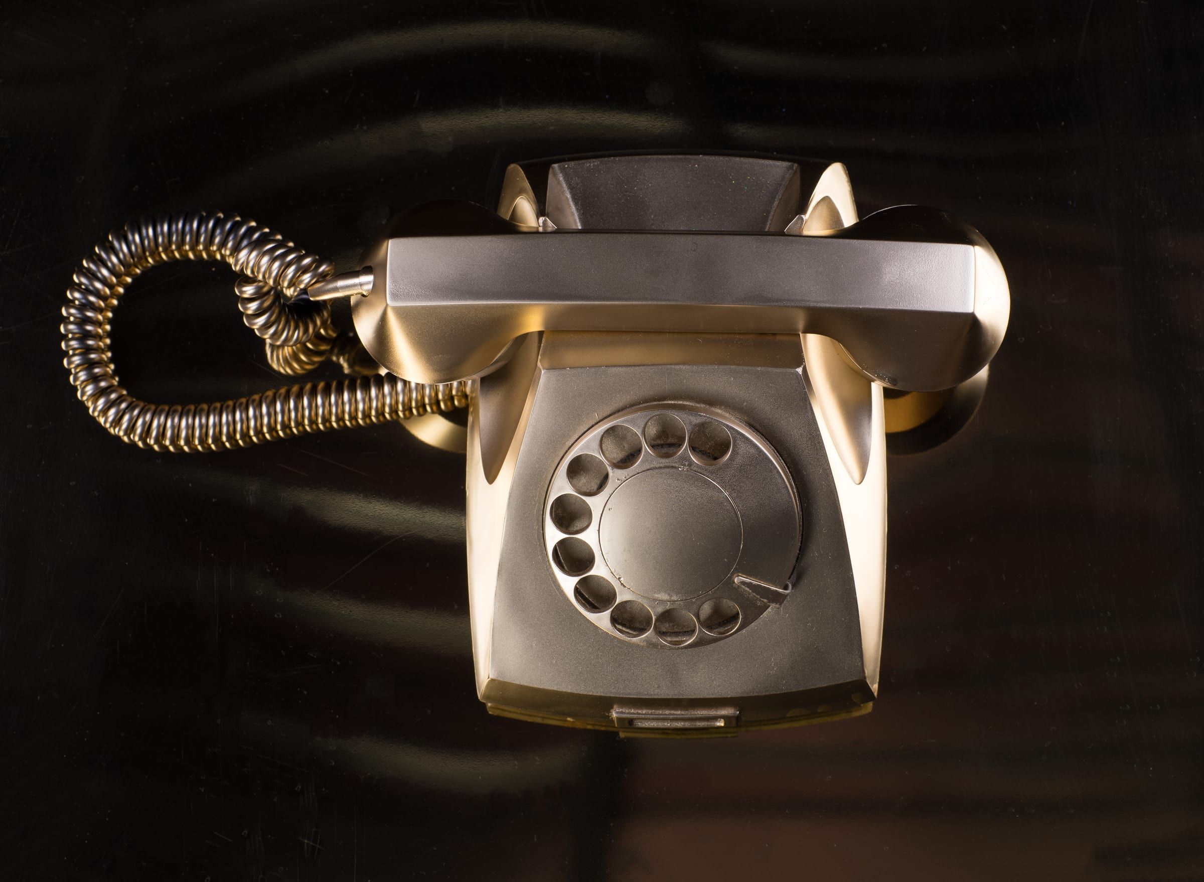 A gold rotary telephone on a black background