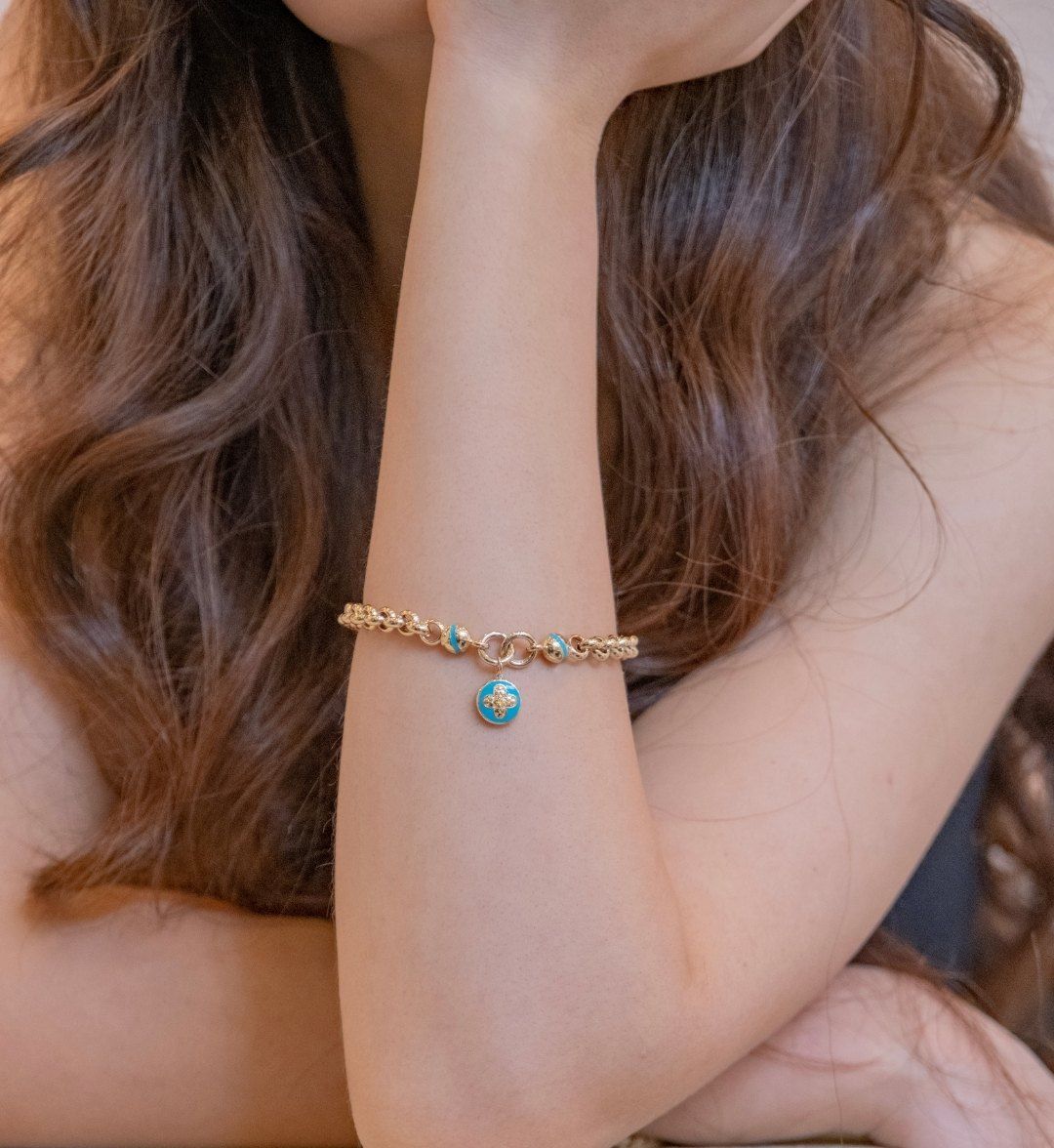 Fine gold chain bracelet with turquoise beads and a round turquoise charm on the wrist