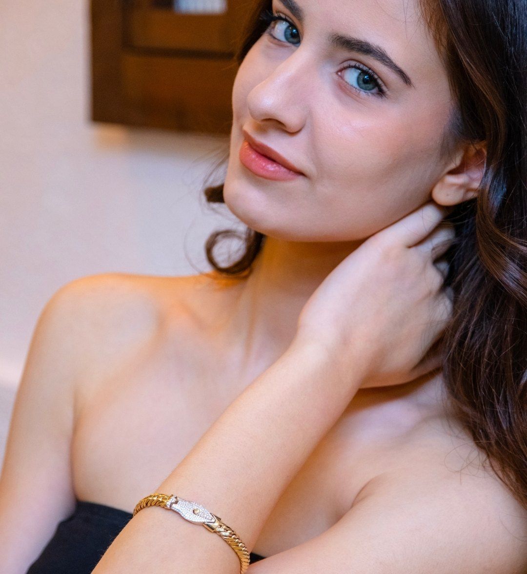 Curb-chain gold bracelet with a white gold plate on a model's wrist