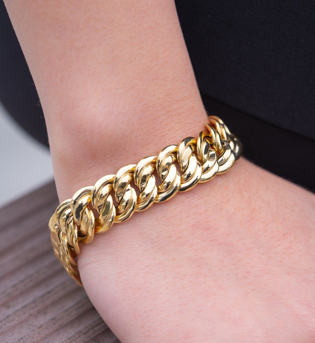 Chunky curb-chain gold bracelet with large polished links on a model's wrist, close-up