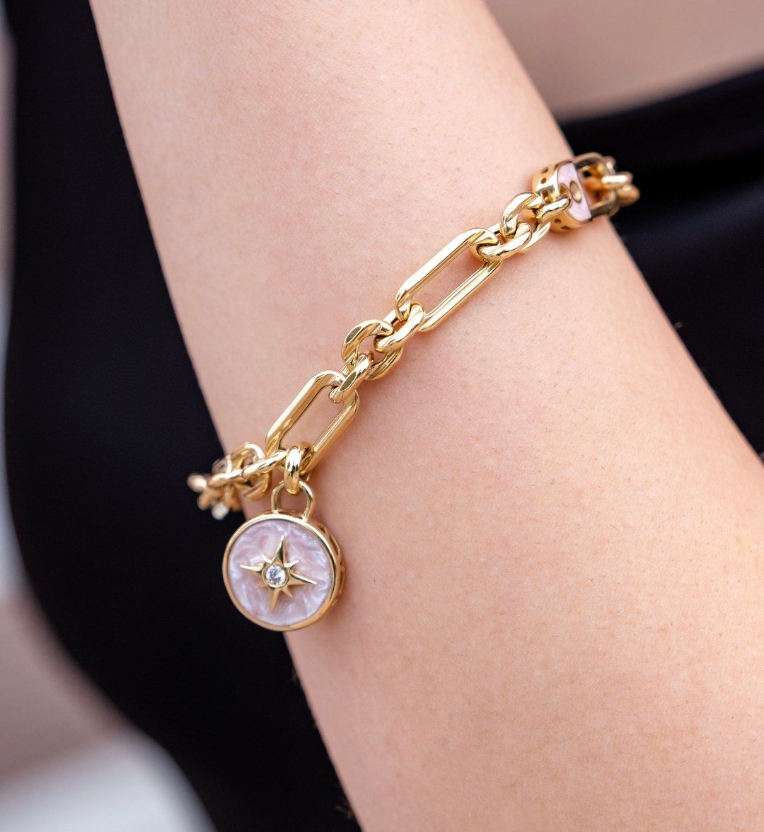 Gold link chain bracelet with a pink enamel star medallion and white stone, on the arm