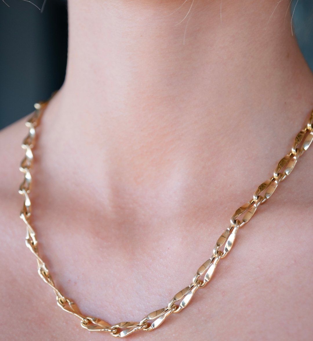 Fancy link necklace of twisted flat links on the neck, close-up at the collarbone