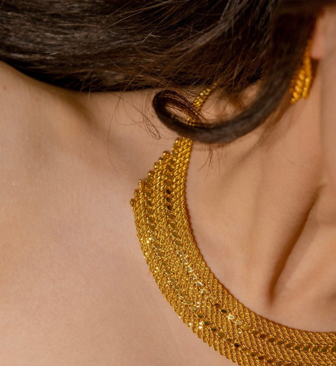 Woven gold collar necklace with rope-twist weave along the neck and shoulder, close-up detail