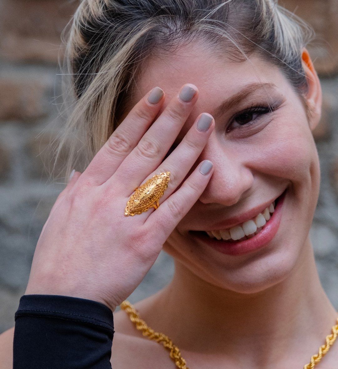 Engraved Ottoman-style ring on a model's hand, worn with a twisted gold chain