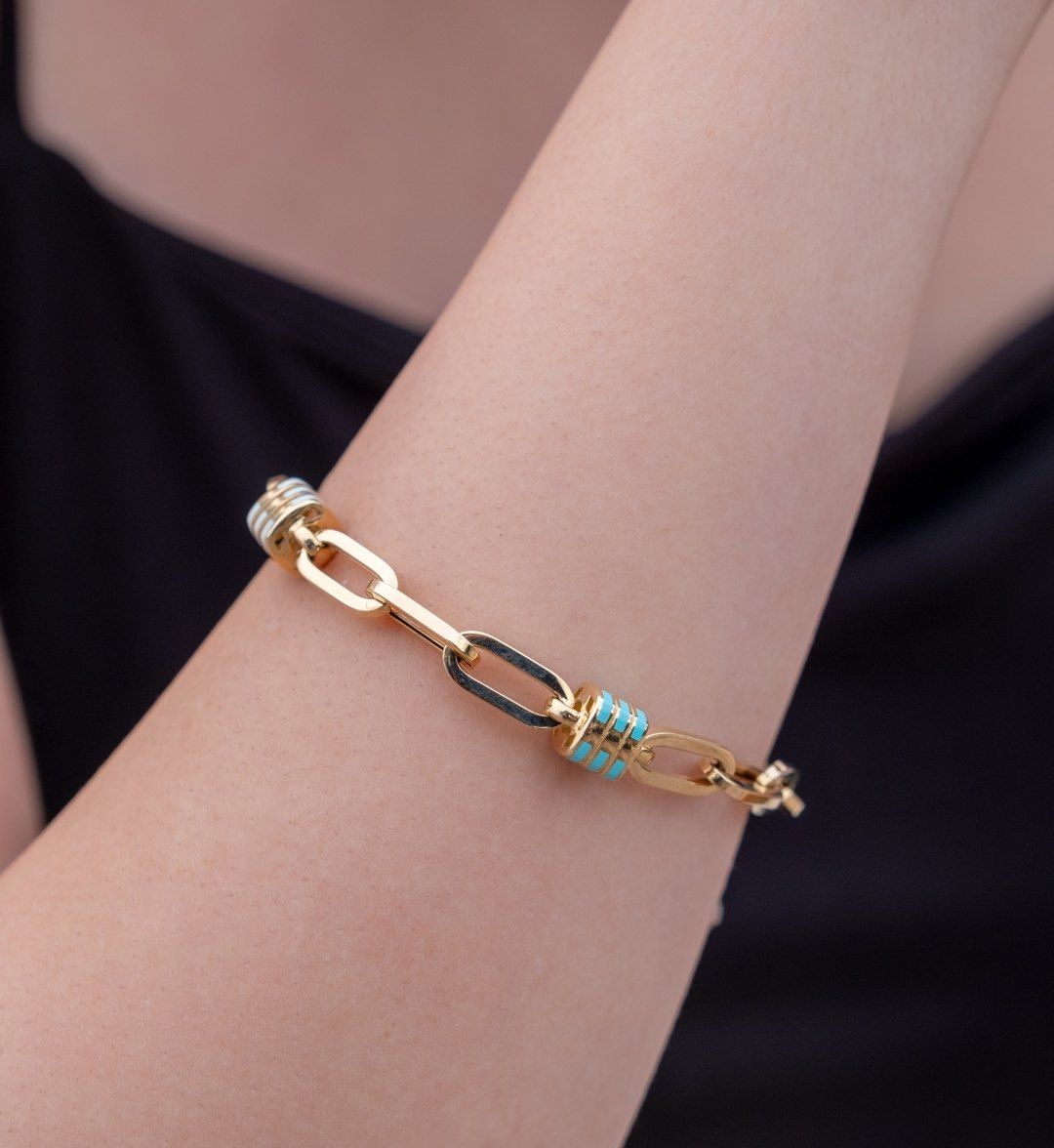 Long-link gold chain bracelet with turquoise and white enamel spacers worn on the arm