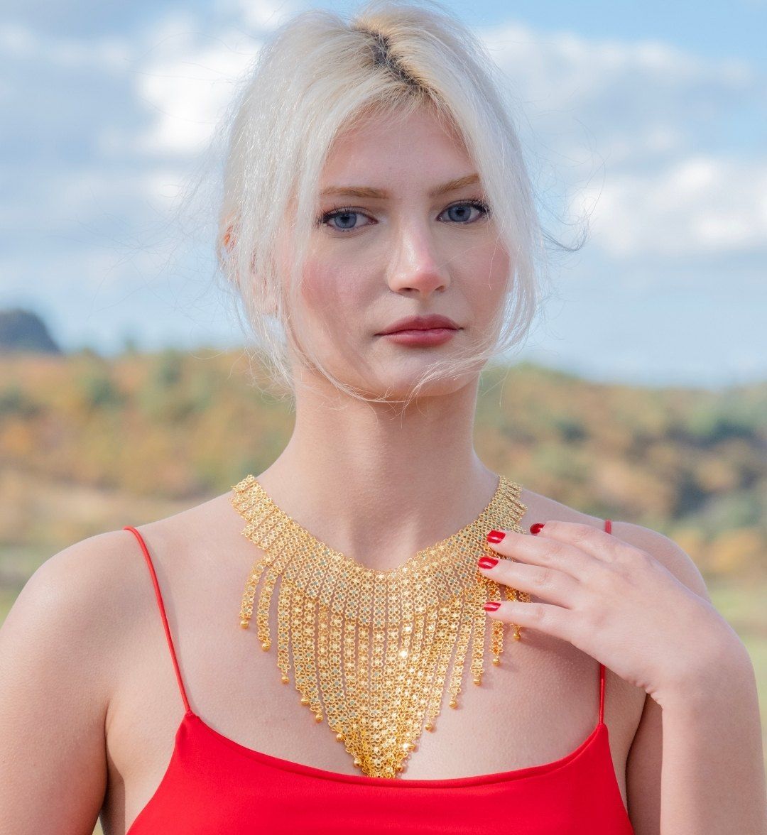 Gold fringe collar of openwork mesh with bead-tipped tassels, worn by a model outdoors