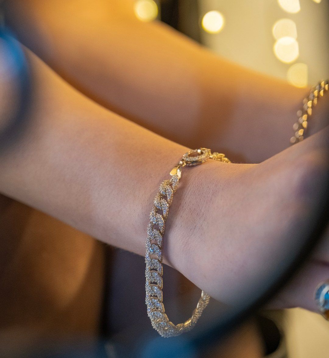 Stone-set tennis bracelet with curb links covered in white stones on a model's wrist