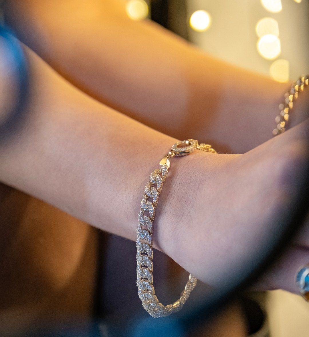 White stone-set tennis bracelet sparkling on crossed arms against soft bokeh lights