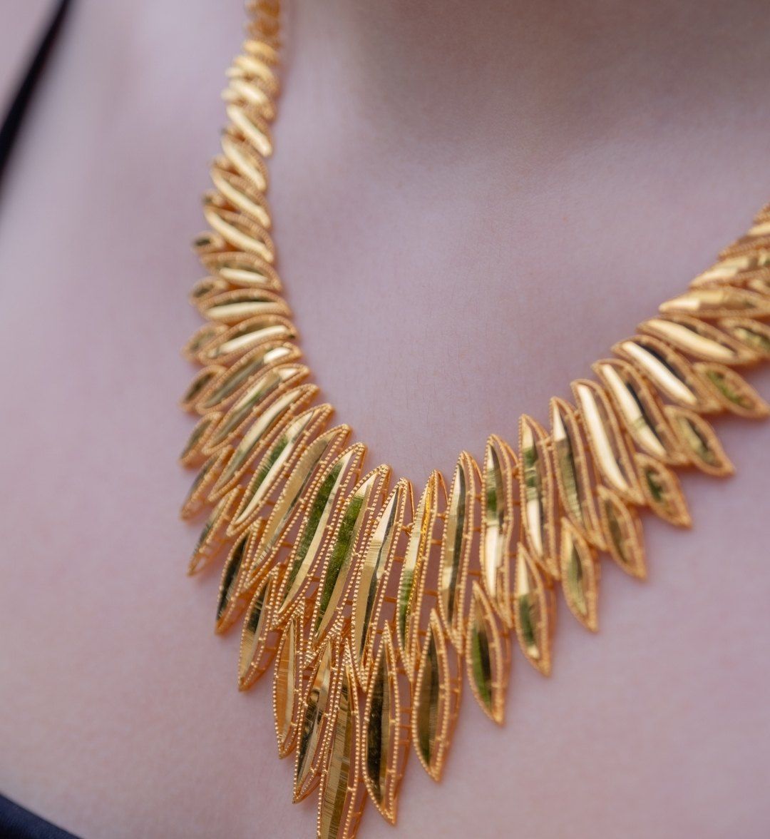 Gold leaf collar made of overlapping pointed leaves on the neck, close-up