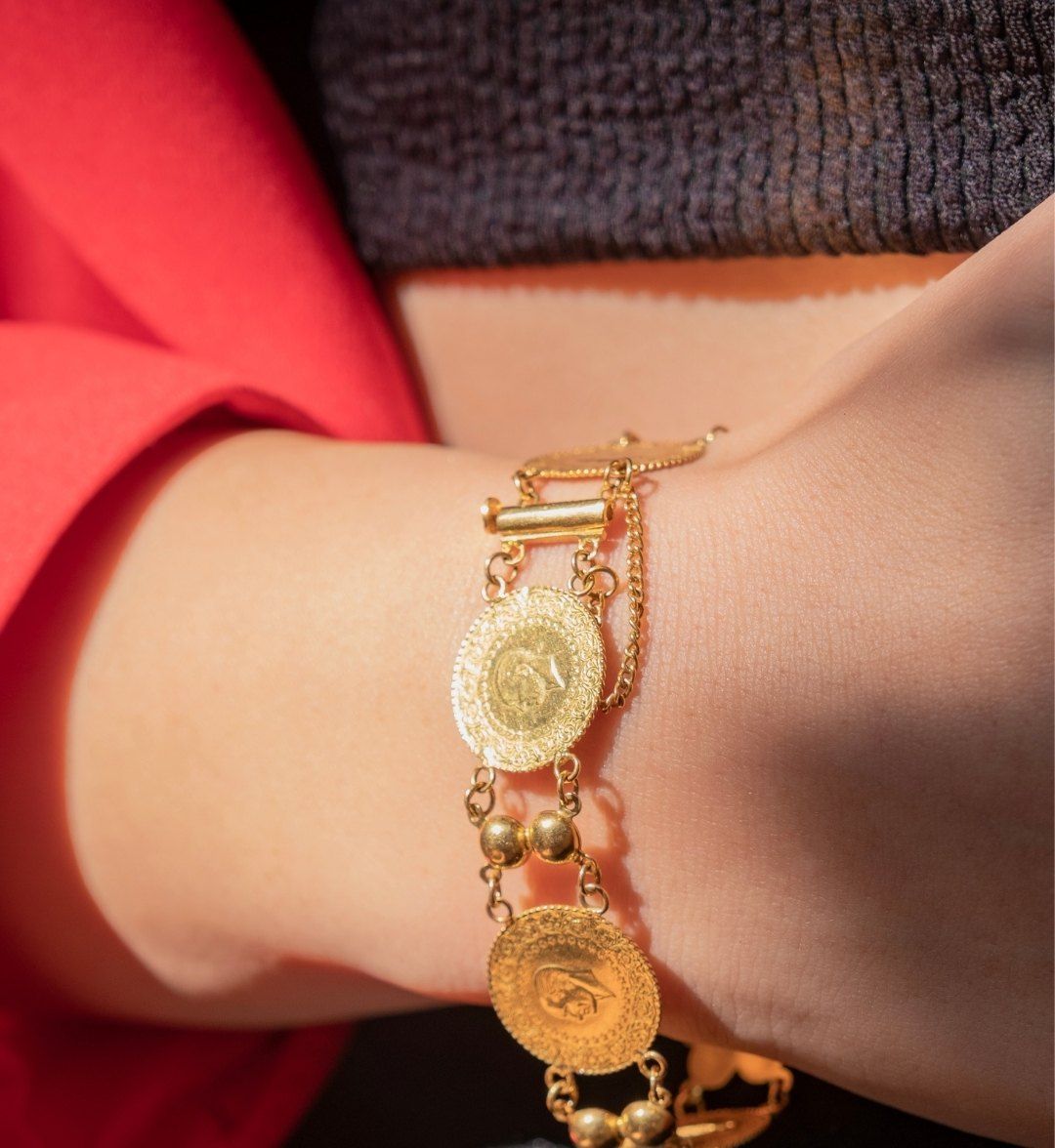 Chain bracelet with quarter gold coins joined by gold bead spacers on a model's wrist